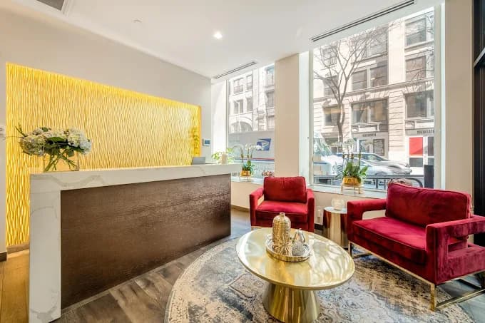 Reception lounge with marble counter, gold accents, and red velvet seating at Mr. Barbosa